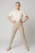 MONROE STORE high-waisted beige yoga leggings with a V-shaped waistband and subtle 'D.A.N.C.E.' logo detail.