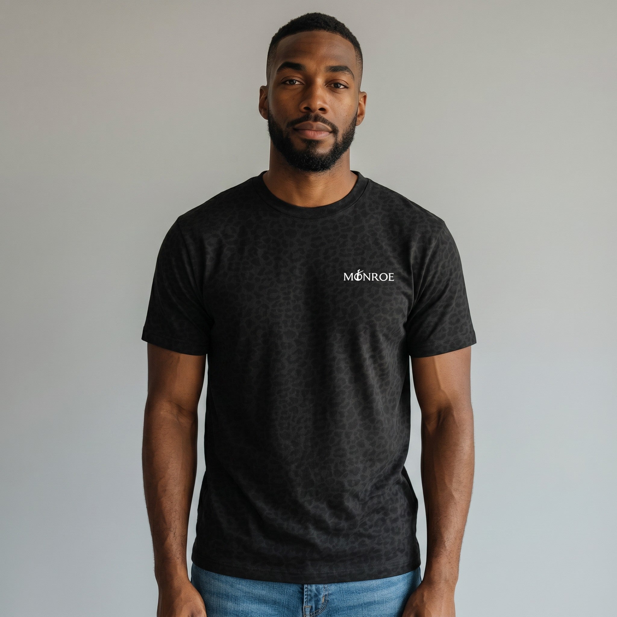MONROE STORE black cotton blend t-shirt with subtle animal print and white logo on chest, worn by a woman with blue jeans.