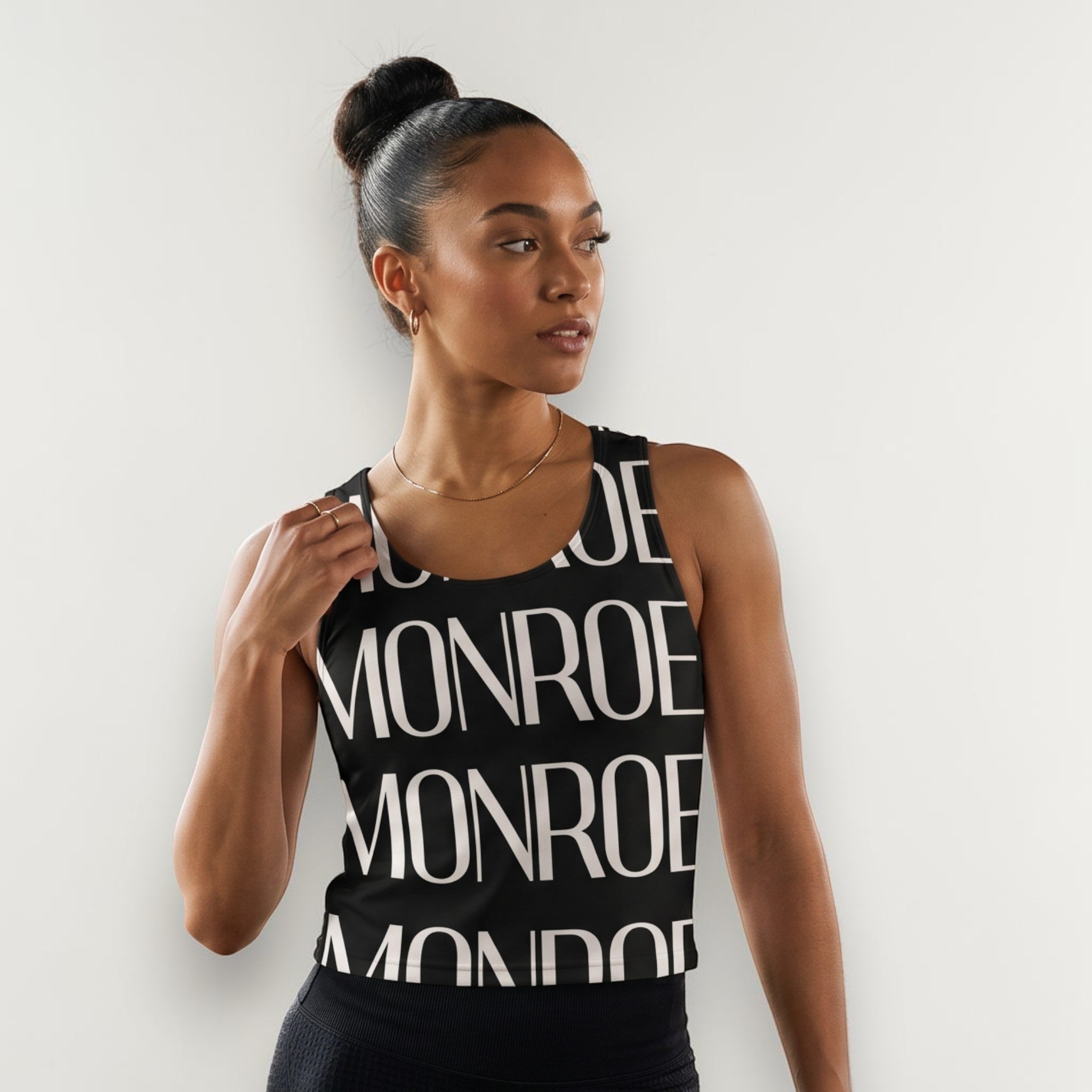 Mujer con camiseta de tirantes negra MONROE STORE con estampado gráfico, en un estudio de danza con espejo.