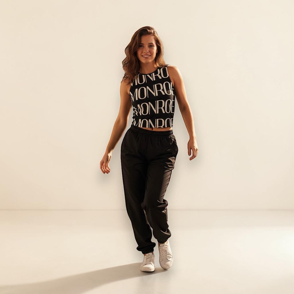 Modelo con camiseta de tirantes negra con logo MONROE STORE, pantalones deportivos negros y zapatillas blancas.