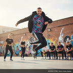 Bailarín saltando con camiseta estampada y sudadera negra en clase de Waacking de MONROE STORE al aire libre.
