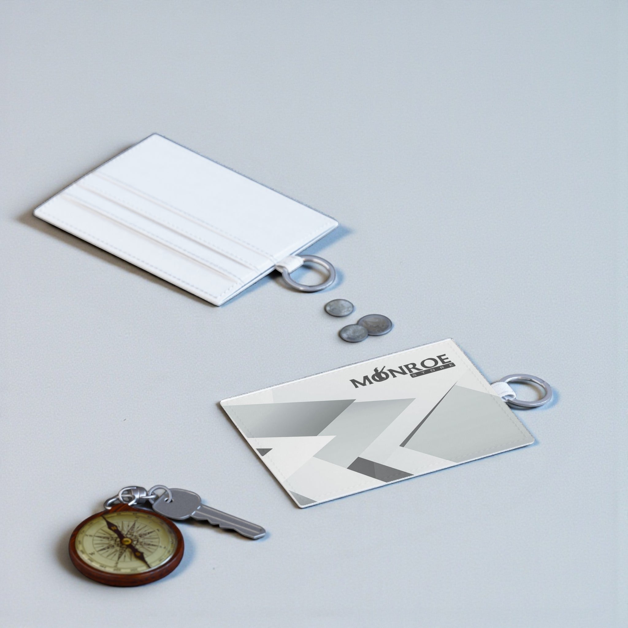 Monroe Store tarjetero blanco de piel sintética con anilla y ranuras para tarjetas, junto a una llave y monedas.